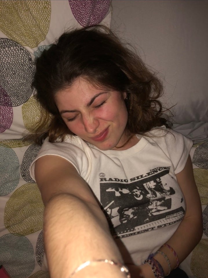 girl takes silly selfie with closed eyes on bed