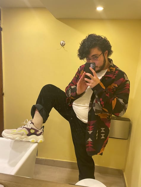 Photo of a young man taking a mirror selfie showing his sneaker